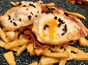 Una foto de Huevos rotos con trufa negra y jamón ibérico