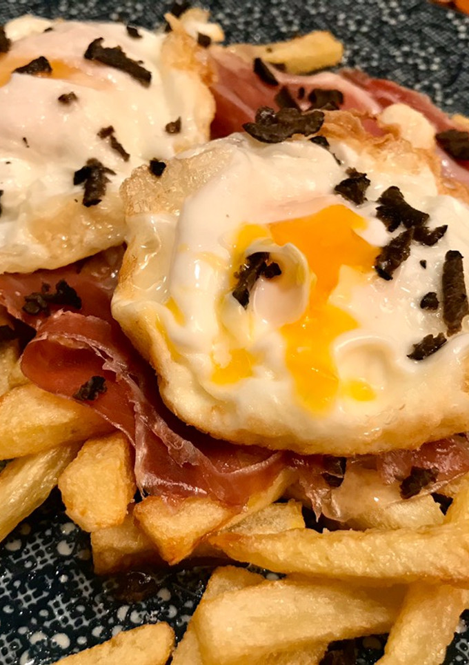 Una foto de Huevos rotos con trufa negra y jamón ibérico