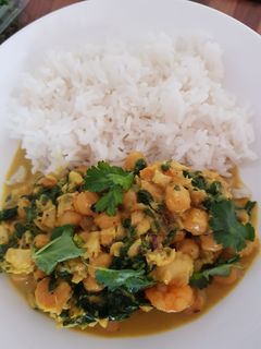 Una foto de Gambas y merluza al curry con garbanzos y espinacas