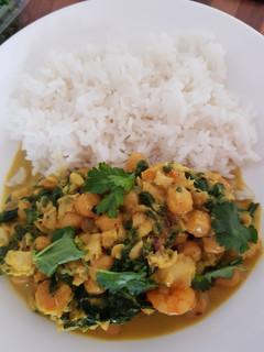 Una foto de Gambas y merluza al curry con garbanzos y espinacas