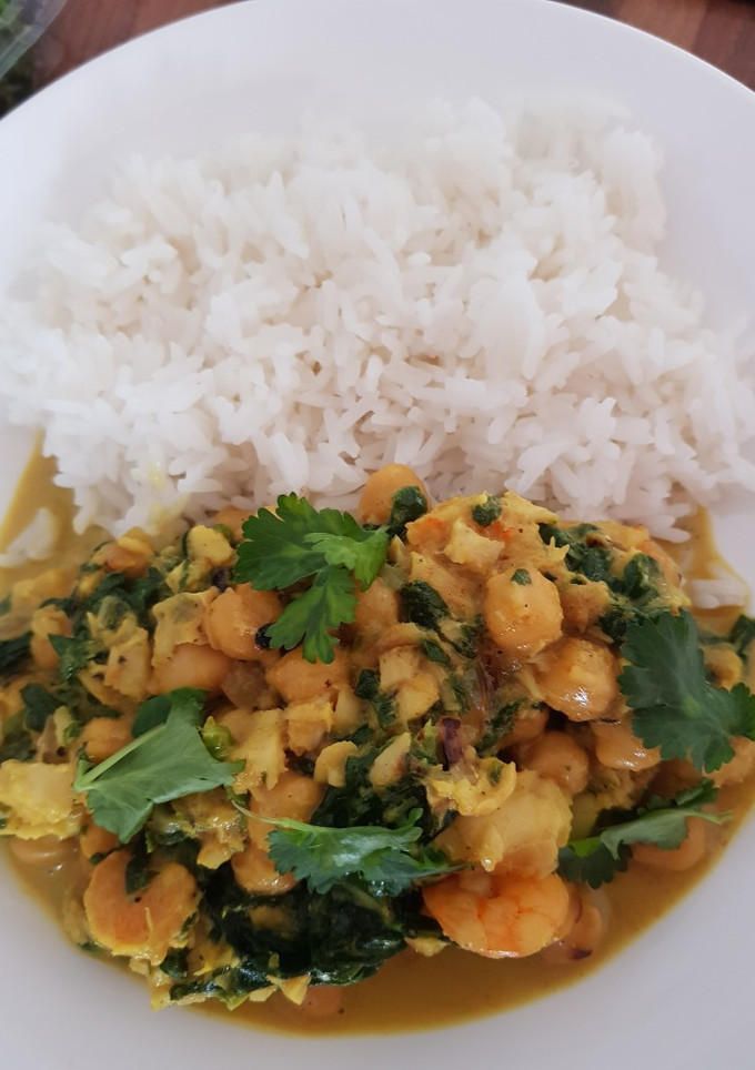 Una foto de Gambas y merluza al curry con garbanzos y espinacas