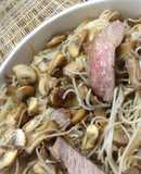 Blushing beef slices and mushrooms in rice noodles