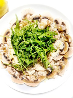 Una foto de Carpaccio de champiñones, rúcula y parmesano