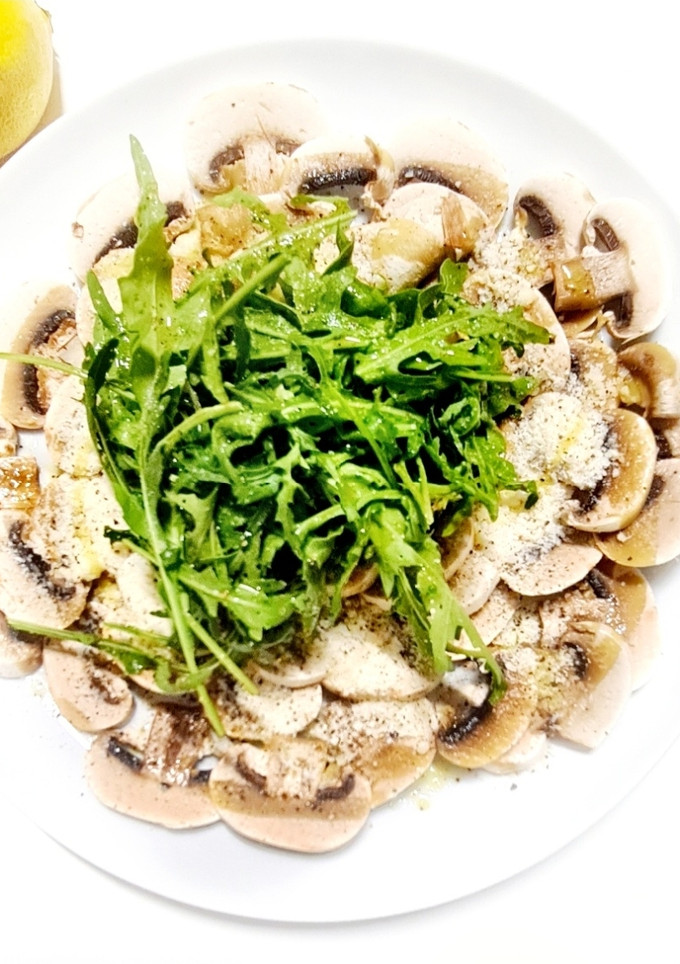 Una foto de Carpaccio de champiñones, rúcula y parmesano