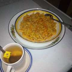 A picture of Mix macaroni jollof and black tea.
