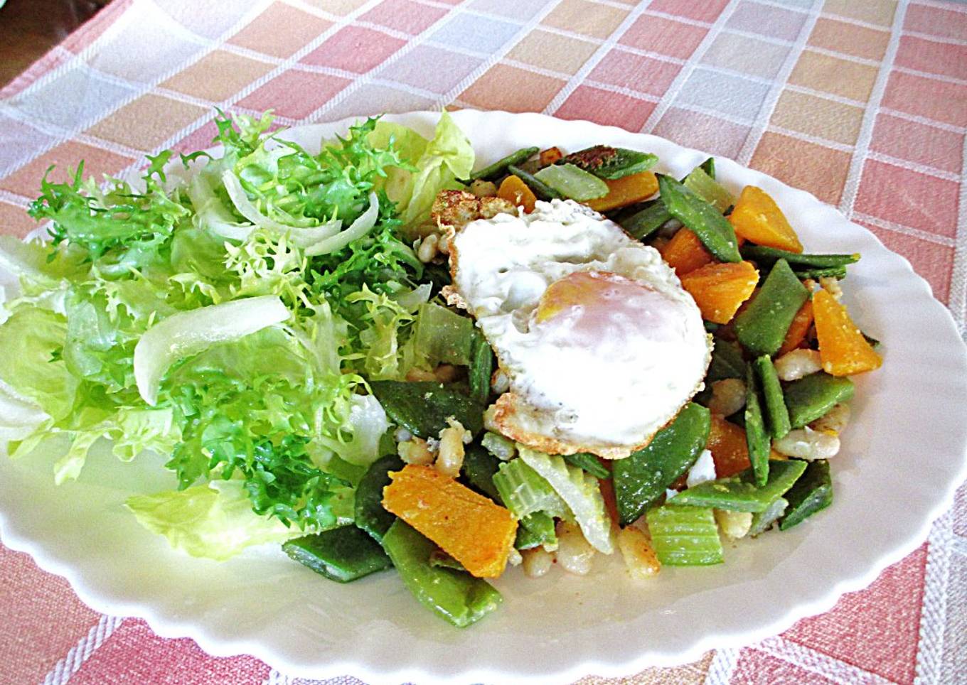 Huevo frito de coral sobre hortalizas y escarola