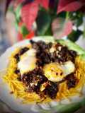 Revuelto de morcilla de León con sofrito de cebolla y pasas sobre cama de patatas paja