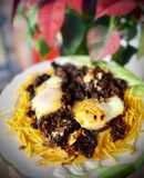 Revuelto de morcilla de León con sofrito de cebolla y pasas sobre cama de patatas paja