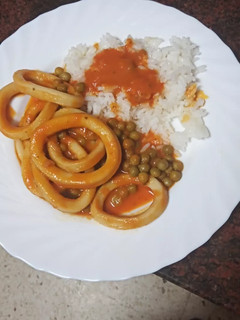Una foto de Calamares en salsa con arroz blanco y guisantes