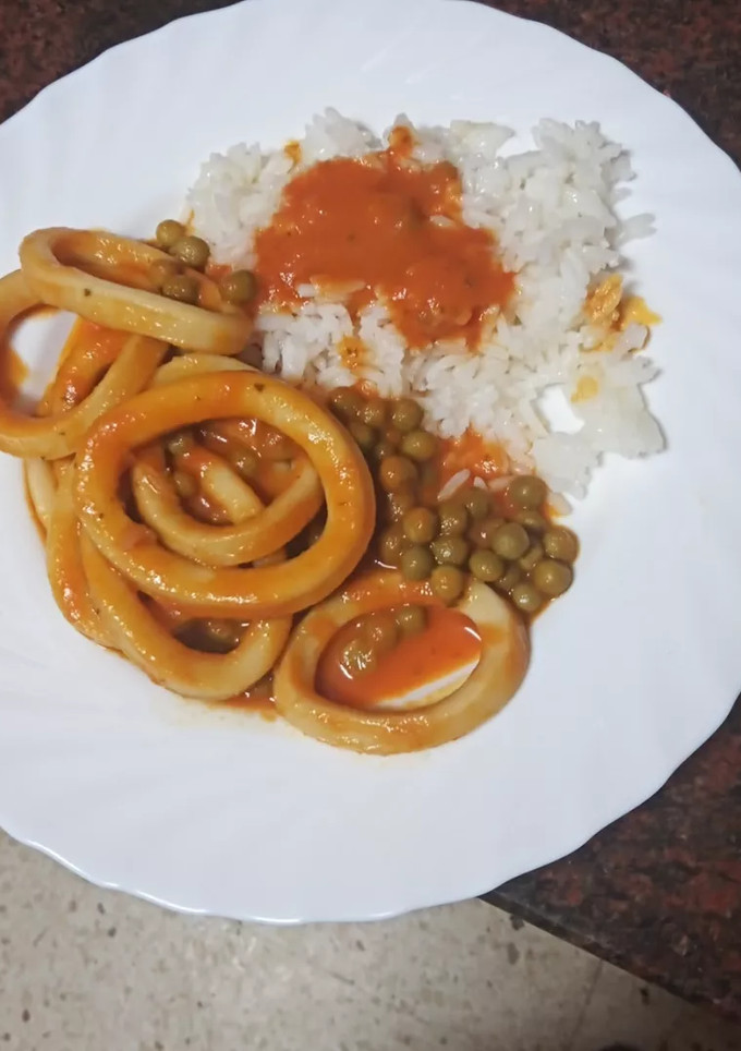 Una foto de Calamares en salsa con arroz blanco y guisantes