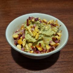A picture of Green hummus with ham and eggs.