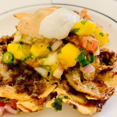 A picture of Loaded Nachos with Mango Salsa, Sour cream and cheese sauce.