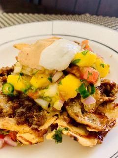 A picture of Loaded Nachos with Mango Salsa, Sour cream and cheese sauce.