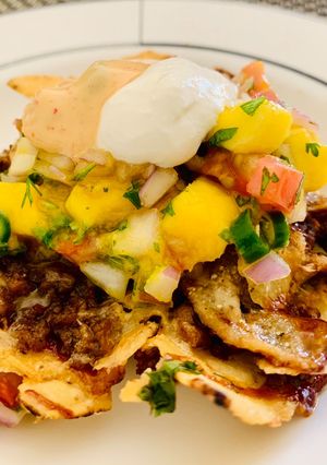 A picture of Loaded Nachos with Mango Salsa, Sour cream and cheese sauce.