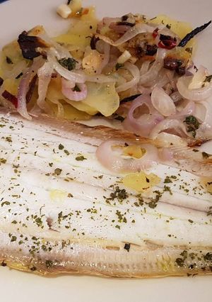 A picture of Dover Sole in the oven with hot and crispy onion and potato on the side.
