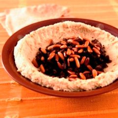 A picture of Hummus with meat and pine nuts.