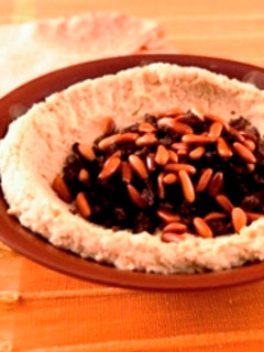 A picture of Hummus with meat and pine nuts.
