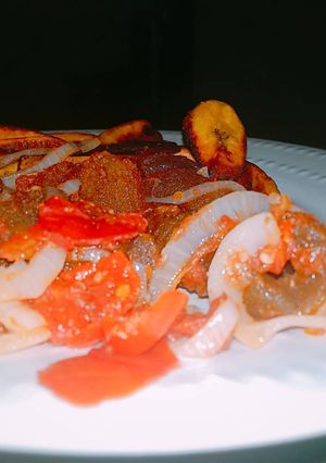 A picture of Pomo with fried plantain and sauce.