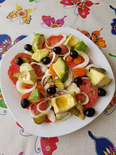 Una foto de Ensalada de tomate, cebolla, encurtidos, cebolla y olivas negras