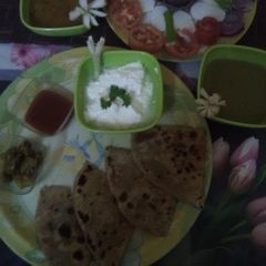 A picture of Muli ka paratha with salad, curd, tomatoe chutney & dhaniya chutney.