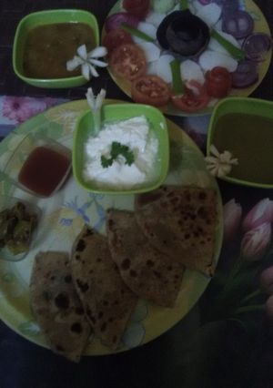 A picture of Muli ka paratha with salad, curd, tomatoe chutney & dhaniya chutney.