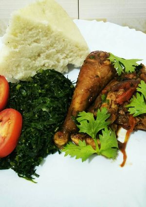 A picture of Wet fried chicken with greens and ugali.