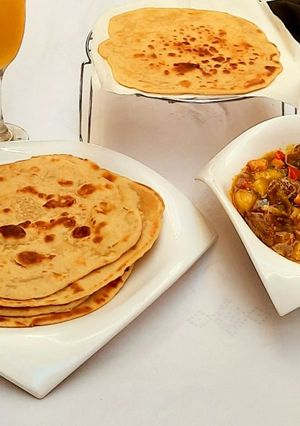 A picture of Garlic naan bread with Beef and veggies soup.