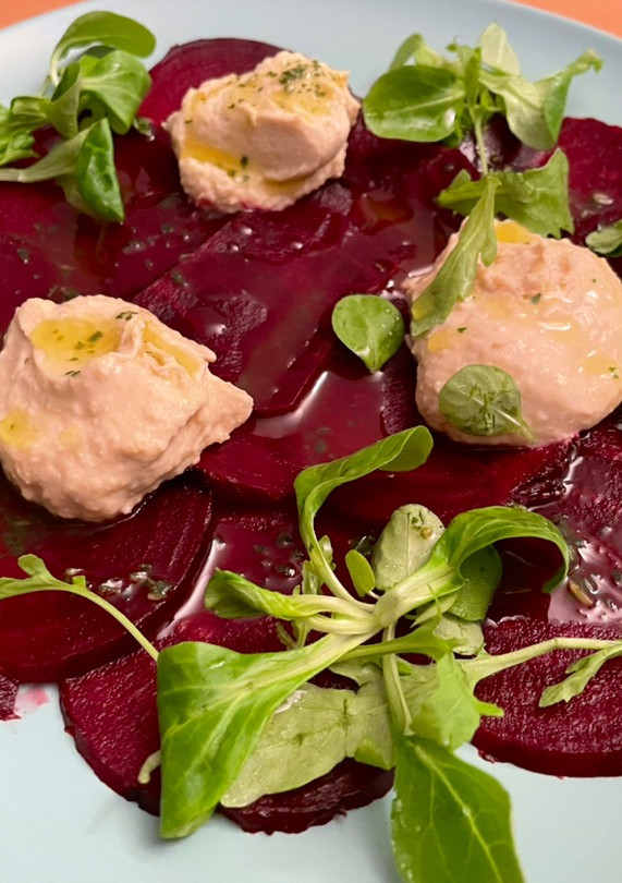 Una foto de Carpaccio de remolacha con hummus y rúcula al toque de albahaca