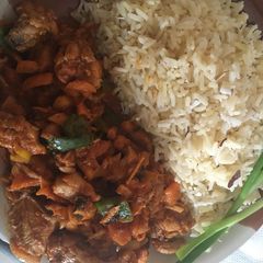 A picture of White coconut rice paired with carrot sauce and chicken.