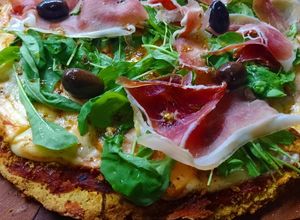Una foto de Pizza de harina de garbanzo y zanahoria 🥕🍕con cubierta de rúcula y jamón crudo