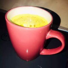 A picture of Turmeric milk with dash of cinnamon powder.