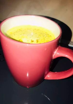 A picture of Turmeric milk with dash of cinnamon powder.