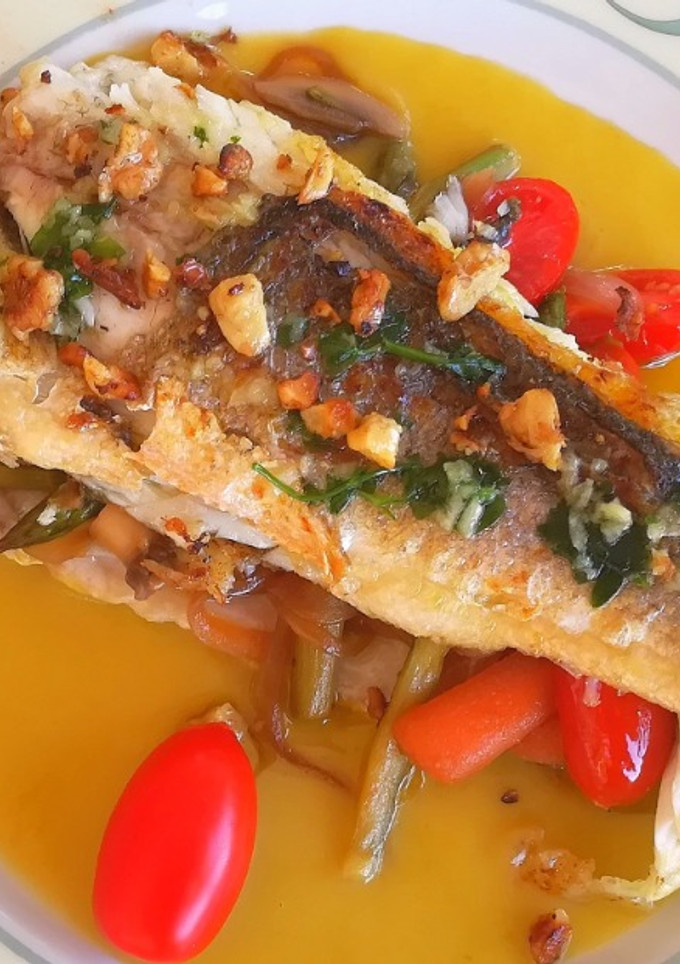 Una foto de Lubina rellena de verduras sobre crema de espárragos