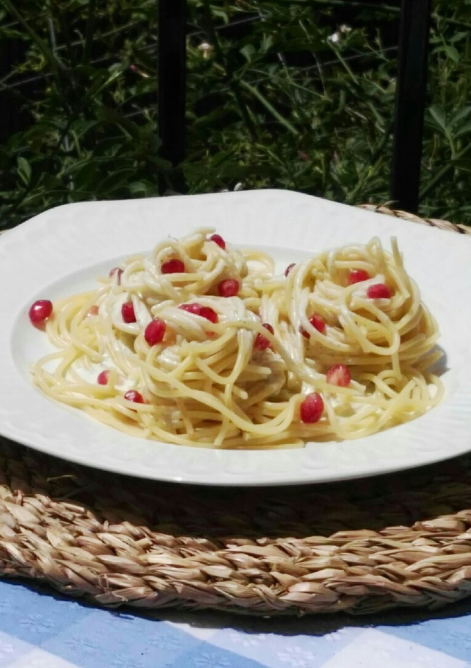 Una foto de Espaguetis con granada y salsa de queso feta