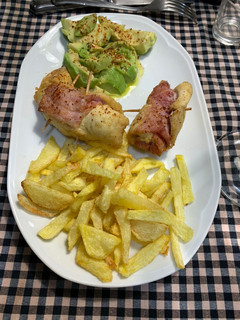 Una foto de Rollitos de pechuga de pollo, jamón York y foie acompañado de aguacate y patatas fritas