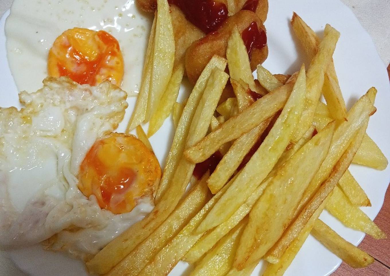 Nuggets de pollo con un par de huevos fritos y papas