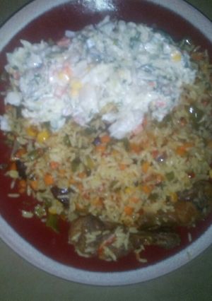 A picture of Fried rice served with vegetable salad and fried chicken.