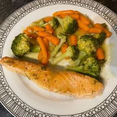 A picture of Salmon with Broccoli and baby carrots in lemon sauce.