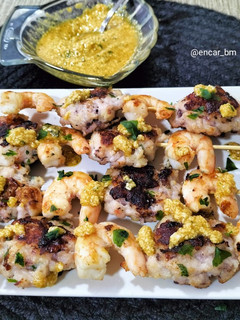 Una foto de Brocheta de langostinos y figatells de calamar con picadillo de almendra