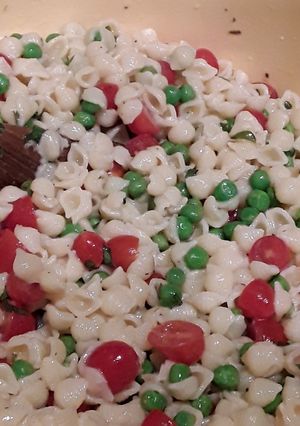 A picture of Pasta salad with peas and tomato.