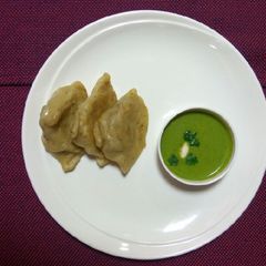 A picture of Steam samosa with yogurt mint sauce.
