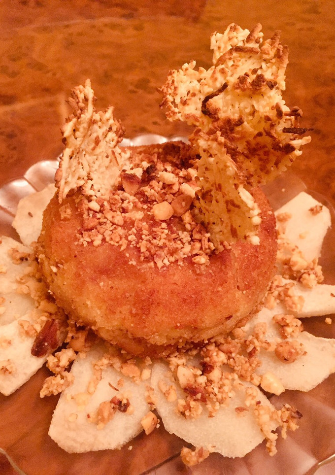 Una foto de Pincho de bola de patata con jamón ibérico, crujiente de queso y cama de pera gratinada