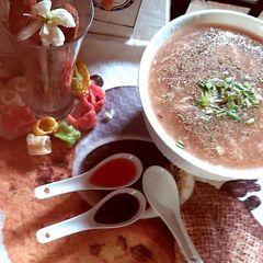 A picture of Chicken soup with green onion and chicken wings.