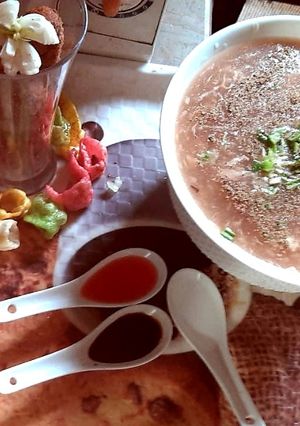A picture of Chicken soup with green onion and chicken wings.