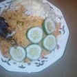 Jollof rice served fried fish, garnished with cucumba and cabbag