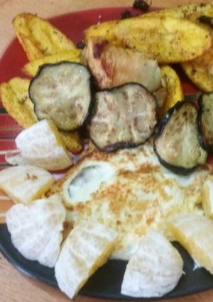 A picture of Fried plantain and eggs with orange and apple.