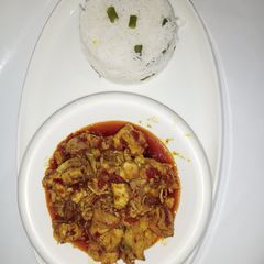 A picture of White rice with chicken sauce.