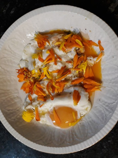 Una foto de Huevos fritos con pétalos de caléndula. "Pon flores en tu boca"