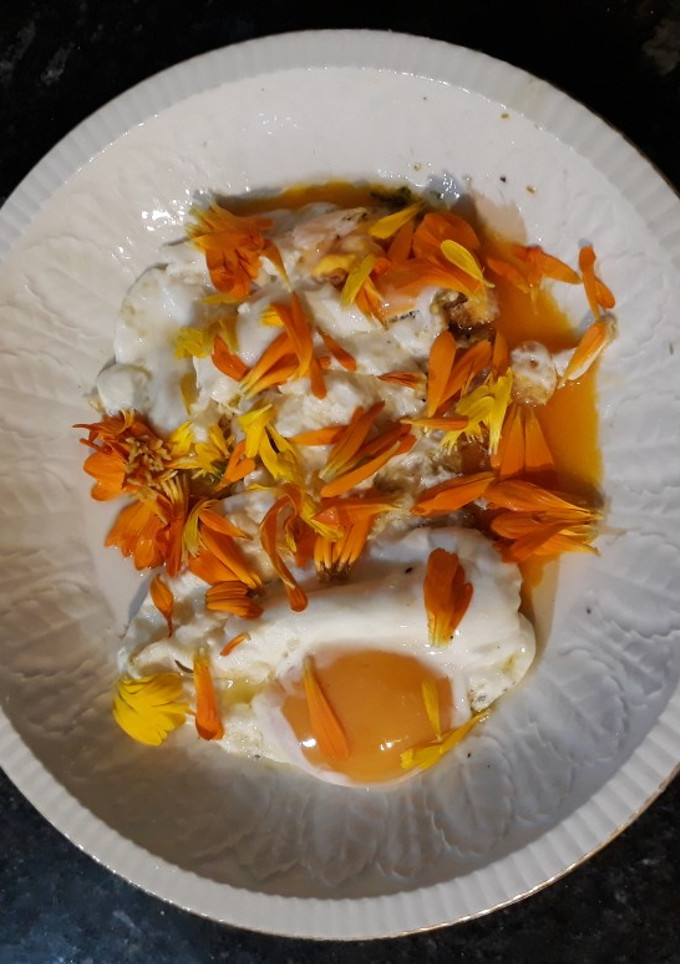 Una foto de Huevos fritos con pétalos de caléndula. "Pon flores en tu boca"