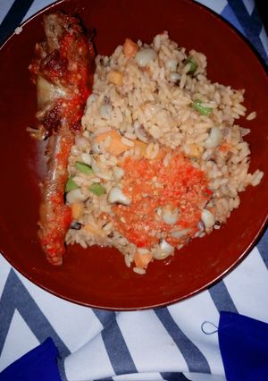A picture of Jellof rice and beans with peppered chicken.